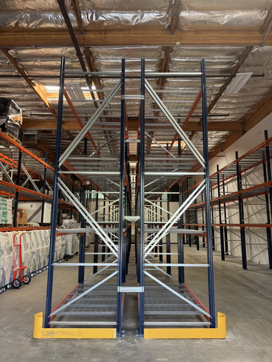 Head-on view down an aisle between cross-braced seismic selective rack rows with row-end protectors